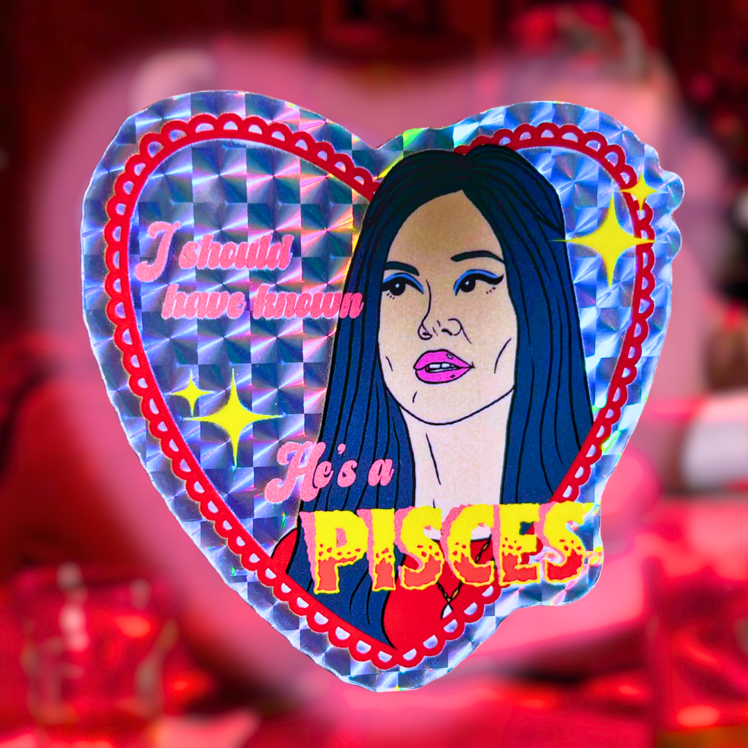 Heart-shaped holographic sticker with Elaine from The Love Witch's face and text 'I should have known He's a Pisces' on a blurred background.