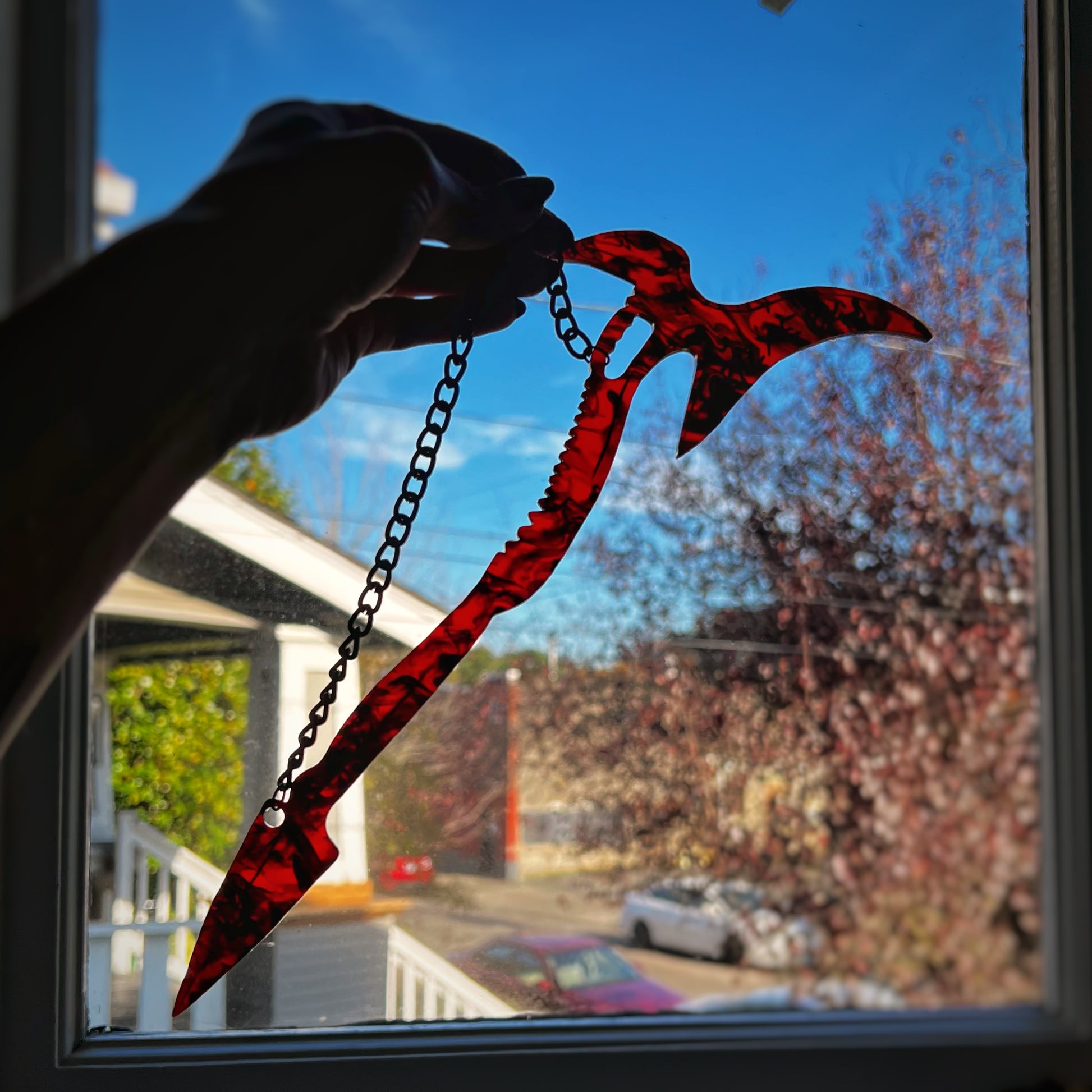 Mandy Movie Merch - A Replica of the weapon from the film, called "The Beast". Large red and black swirled syth-axe hybrid hanging from a black chain.